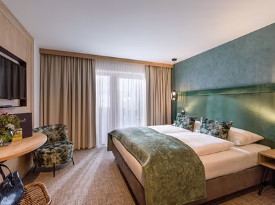 Zimmer in grün gehalten mit Doppelbett und Sitzmöglichkeit