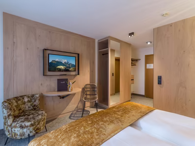 In gold gehaltener Raum mit Kasten, Sitzgelegenheit und TV an der Wand