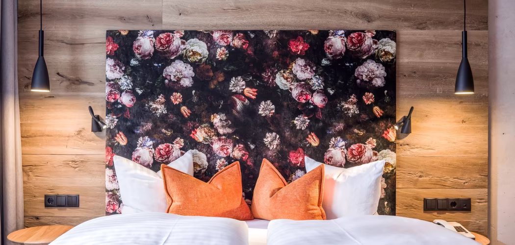 Holztäfelung hinter dem Bett, florales Rückenteil mit orangen Zierkissen auf dem Doppelbett