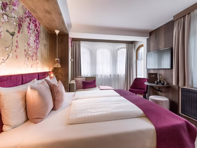 In beeren Farbe gehaltener Raum mit Doppelbett, Couch und TV